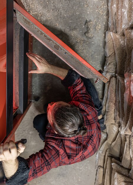 The young man looking into a solid fuel boiler, working with biofuels, economical heating, top view.