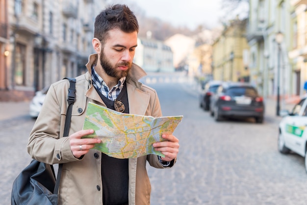 Young man looking for way on destination map; enjoying vacation