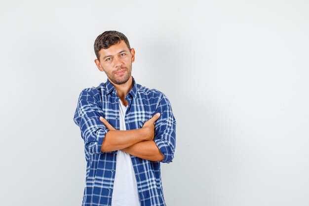 Young man looking with crossed arms in shirt front view.