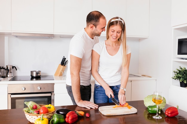 Young man loving her girlfriend cutting the carrot with knife