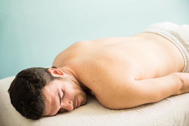 Young man lying on a massage bed and waiting for a therapist in a spa