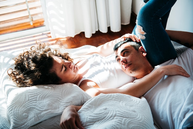 Free photo young man lying on woman belly on bed