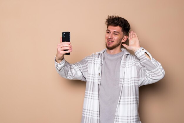 Young man make video call on phone on beige background