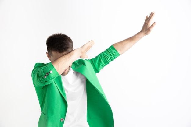 Young man makes a dab movement with his arms on a gray background. Human emotions, facial expression concept