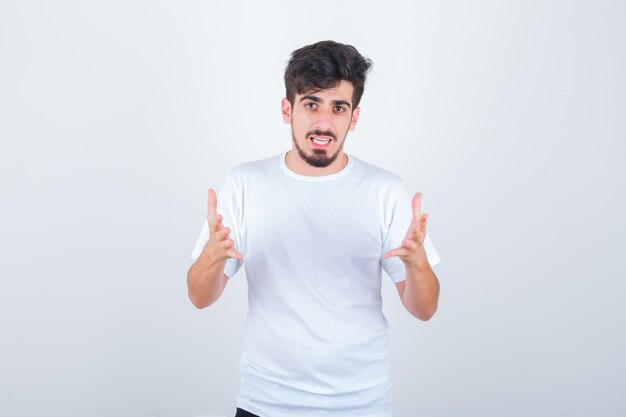 Young man making giving pose in t-shirt and looking happy