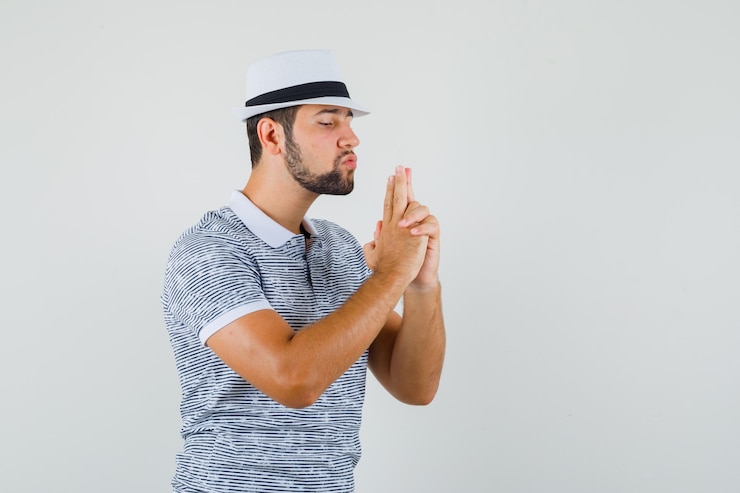 無料Photo 縞模様のtシャツ、帽子で銃のジェスチャーをし、集中して見える若い男。正面図。