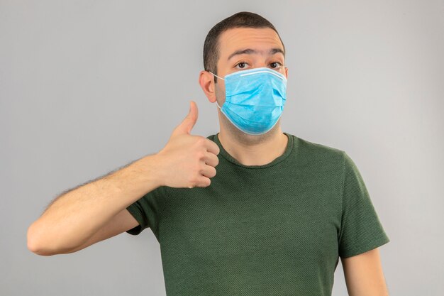 Young man in medical mask doing ok sign, thumb up with fingers isolated on white