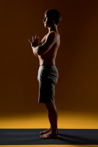 Young man meditating on yoga mat