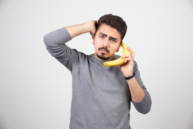 Модель молодого человека держит банан в качестве телефона.