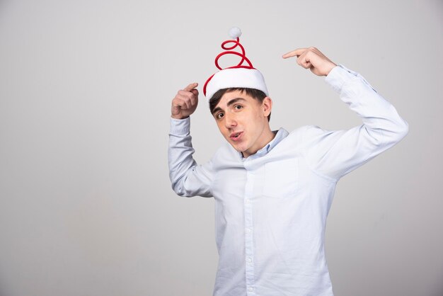 Модель молодого человека стоя и указывая на рождественскую шляпу