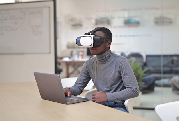 Free photo young man in an office with a virtual mask and a computer