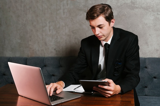 Молодой человек в офисе работает на ноутбуке