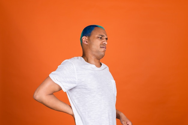 Young man on orange wall feeling pain back suffering unhappy