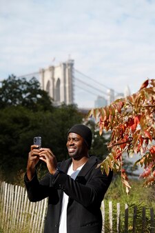 一人で街を探索し、スマートフォンで写真を撮る屋外の若い男