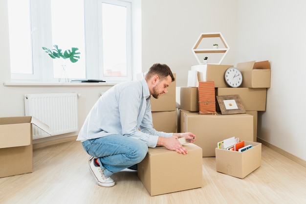 Young man packing the cardboard boxes at home