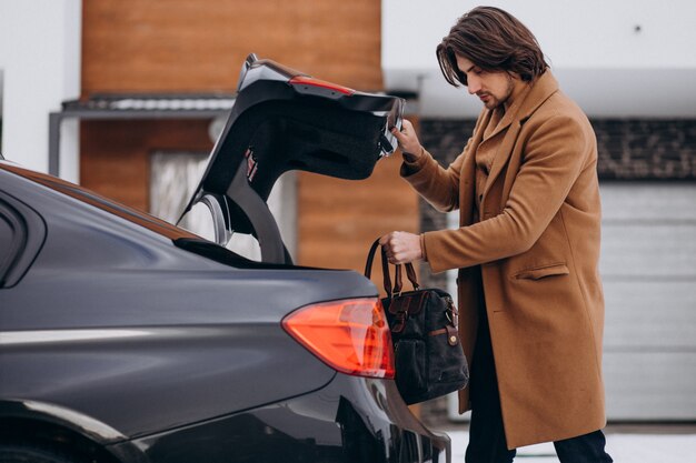 Young man packing his bag into a car