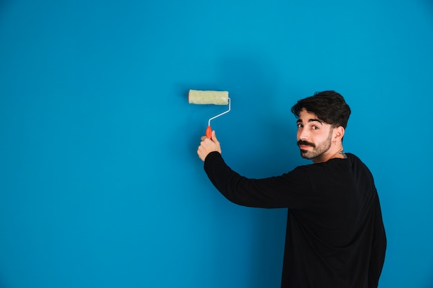 Young man painting blue wall