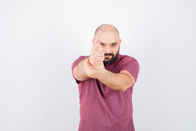 Foto gratuita giovane in maglietta rosa che mostra il gesto della pistola, vista frontale.