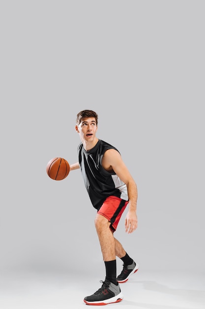Молодой человек играет в баскетбол в одиночку