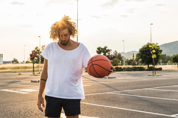 Молодой человек играет в баскетбол в суде