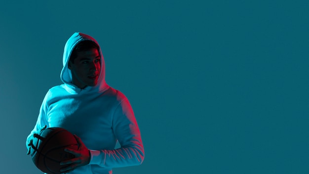 Young man playing basketball with cool lights with copy space