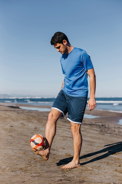 Young man playing football at the beach