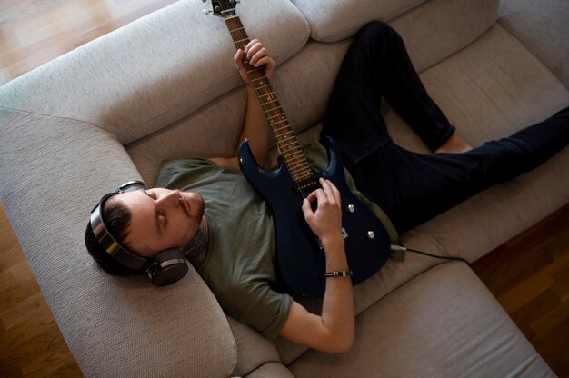 Молодой человек играет на гитаре дома