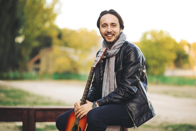 Young man playing on guitar at the lake