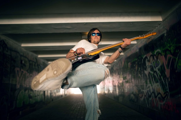 Giovane che suona la chitarra in una strada.