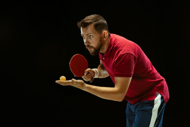 Free photo young man playing table tennis on black studio