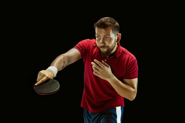 Free photo young man playing table tennis on black studio