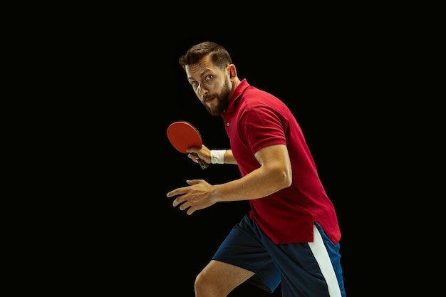 Young man playing table tennis on black 