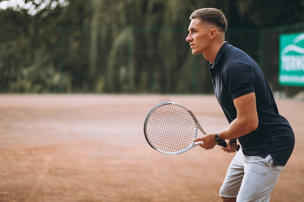 Young man playing tennis at the court