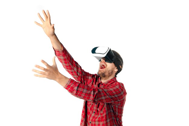 Young man playing using virtual reality headset isolated on white studio wall