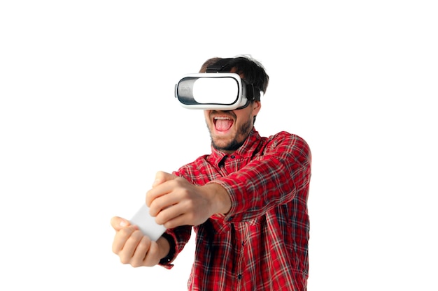 Free photo young man playing using virtual reality headset isolated on white studio wall