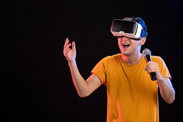 Молодой человек играет в виртуальной реальности и поет на темной поверхности