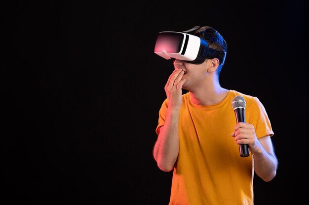 Young man playing virtual reality and singing on dark surface