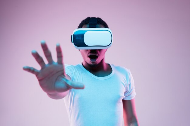 Молодой человек играет в VR-очках в неоновом свете