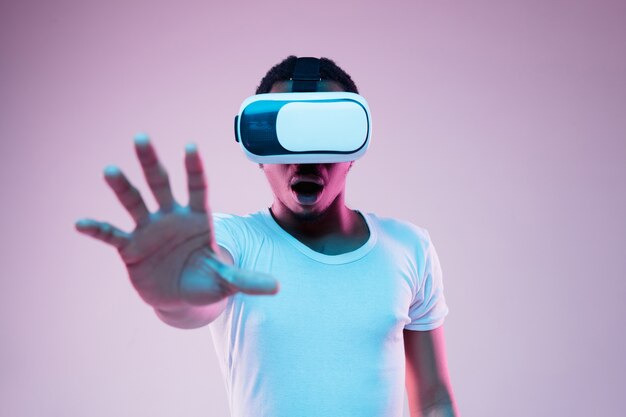 Young man playing in VR-glasses in neon light