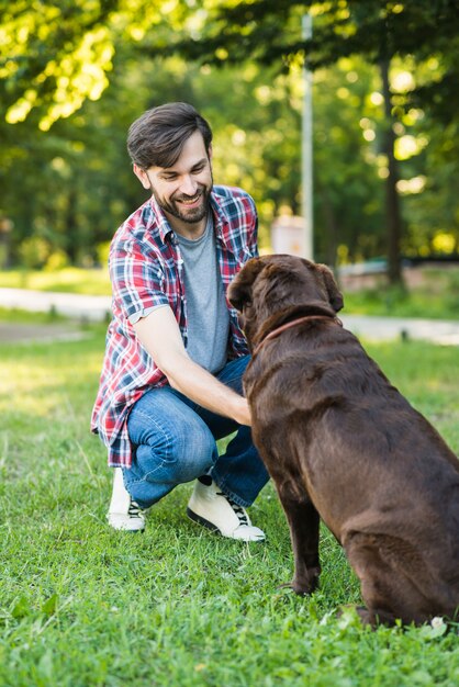 Young man playing with his dog on green grass