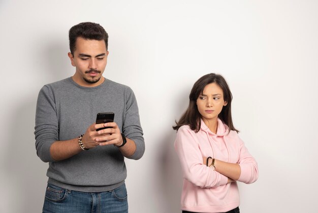 Young man playing with his telephone while his lover looking at. 