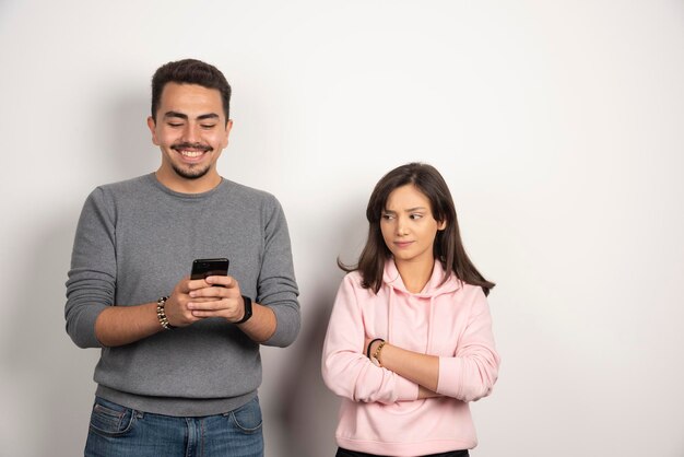 Young man playing with his telephone while his lover looking at. 