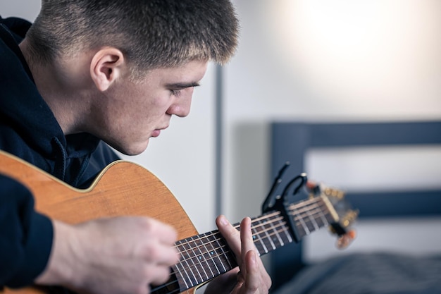 若い男がアコースティックギターを弾く