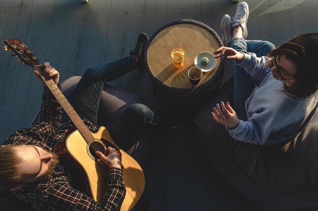 A young man plays the guitar for a girl top view