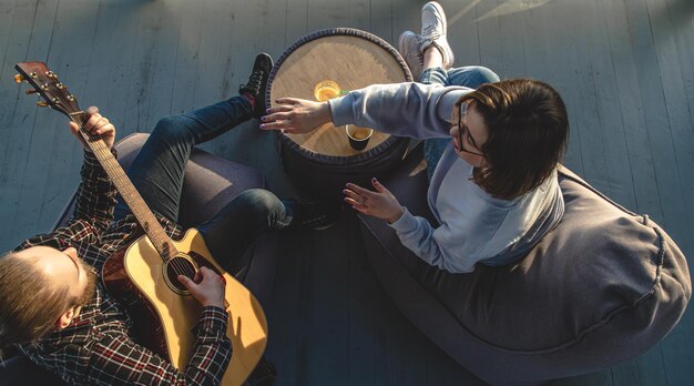 A young man plays the guitar for a girl top view