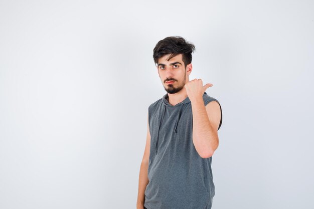 Young man pointing away in gray t-shirt and looking serious
