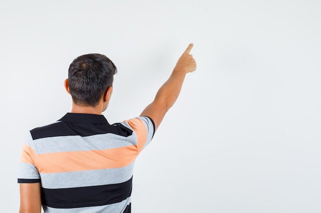 Young man pointing away in t-shirt and looking focused