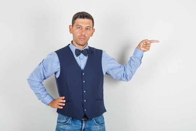 Young man pointing away with hand on waist in suit, jeans