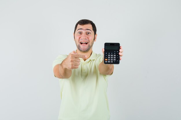 若い男がTシャツで電卓を指して、幸せそうに見える、正面図。