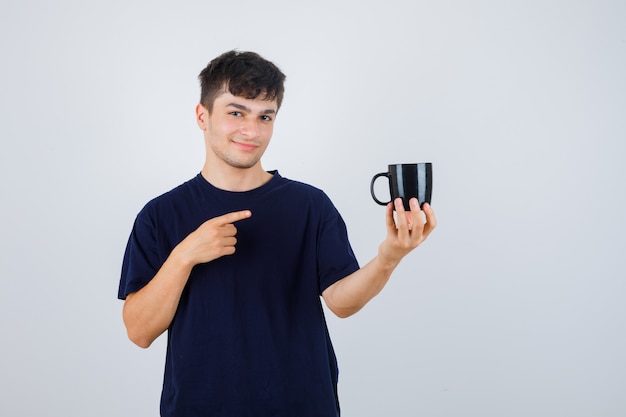 黒のTシャツでカップを指して、自信を持って、正面図を探している若い男。